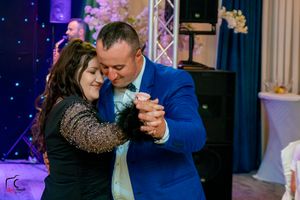 Couples dancing together at an elegant event with blue and purple lighting effects in the background.