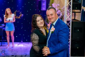 Dance party scene with couples dancing under vibrant blue and purple stage lighting.
