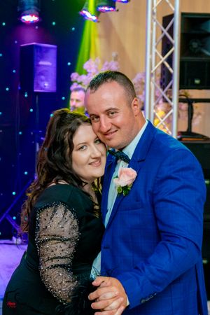 Couples sharing intimate dance moments under atmospheric blue and purple lighting at an event.