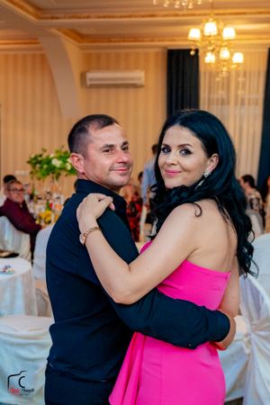 Couples dancing in formal attire at an elegant reception with warm lighting and white table settings.