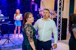 Event space with stage lighting and couples dancing during a formal celebration.