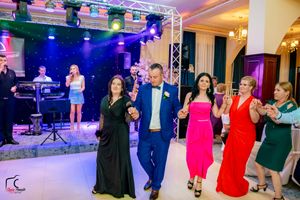 Formal event space with colorful lighting showing multiple couples dancing on the floor.