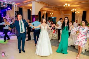 Wedding celebration with guests dancing in formation on a brightly lit dance floor.