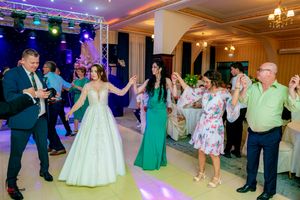 Wedding party performs synchronized dance moves during reception under colorful stage lighting.