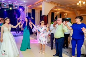 Guests join in traditional line dance at wedding reception with professional lighting setup.