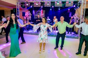 Wedding guests hold hands in a circle while dancing during reception with blue stage lights.