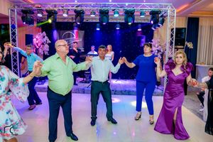 Wedding party dances in formation under professional lighting at elegant reception venue.