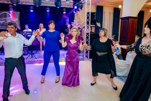 Guests perform coordinated dance moves during wedding reception with stage lighting.