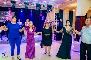 Wedding guests dance in line formation during evening reception with dramatic lighting.