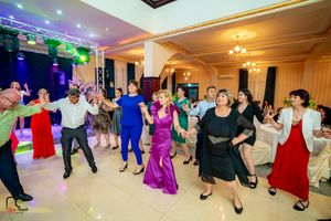 Wedding party and guests perform a traditional line dance in an ornate ballroom with mood lighting.