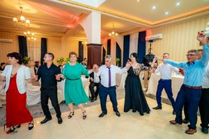 Panoramic view of wedding guests forming a connected dance line in an elegant reception venue.