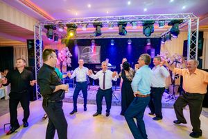 Wide shot of wedding reception dance floor with guests performing synchronized line dance moves.