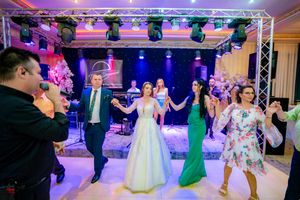 Festive wedding reception features coordinated line dancing under dramatic purple lighting effects.