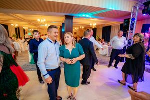 Wedding celebration in a banquet hall with colorful uplighting and guests dancing on the dance floor.