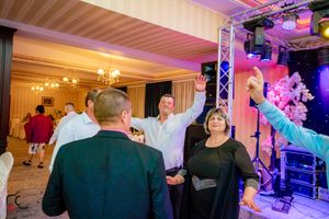 Panoramic view of a wedding reception venue with purple lighting and guests dancing.