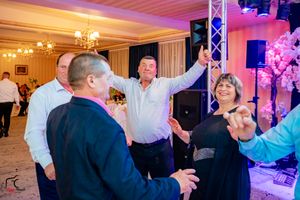 Lively dance floor scene at a wedding reception with dramatic purple and pink lighting effects.