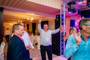 Wedding party dancing and celebrating in an elegant ballroom with professional lighting setup.