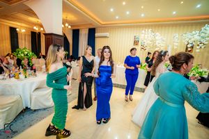 Wedding reception venue decorated with crystal chandeliers and guests in coordinated blue and teal attire.