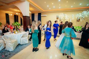 Elegant ballroom wedding reception with guests in blue and teal dresses dancing under chandeliers.