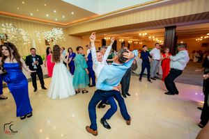 Panoramic view of wedding guests dancing and celebrating in an elegantly lit reception hall.