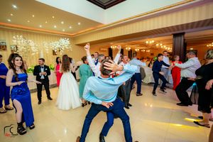 Wedding celebration showing guests dancing in a spacious ballroom with modern lighting.