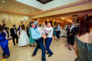 Couples dancing together at a wedding celebration in a warmly lit banquet hall.