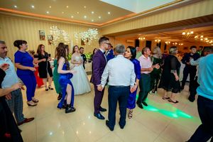 Guests enjoying a lively dance party at an indoor wedding reception with decorative lighting.