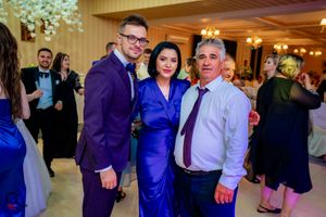 Wedding guests in formal attire posing together at an elegant indoor reception venue.