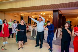 Wedding guests dancing and celebrating on the dance floor at an indoor reception.