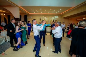 Wedding guests dancing in pairs across a brightly lit ballroom floor.