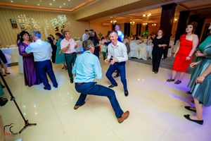 Wedding reception dance floor filled with guests dancing under colorful lighting and decorative ceiling fixtures.