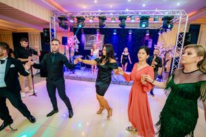 Panoramic view of an elegant ballroom with guests dancing under purple and blue lighting effects.