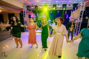 Wide shot of a wedding reception venue with colorful lighting and guests dancing on the dance floor.