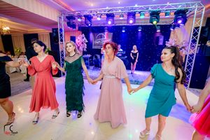 Panoramic view of a wedding celebration with guests dancing under vibrant lighting in an elegant ballroom.