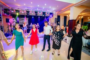 Wide angle view of a wedding reception ballroom with guests dancing under dramatic purple lighting.