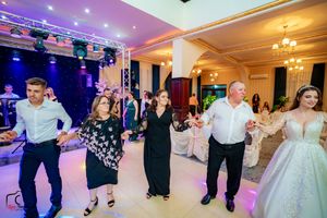 Wedding celebration in a grand ballroom with dramatic lighting and guests dancing across the floor.
