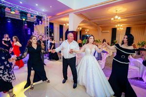 Panoramic shot of an elegant wedding venue with guests dancing under warm and cool lighting effects.
