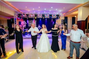 Panoramic capture of a wedding reception ballroom with guests dancing under professional lighting setup.