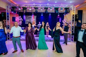 Party guests dance in formation under professional stage lighting at an indoor celebration.