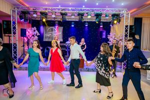 Party guests dance together on illuminated floor under colorful stage lighting and truss system.