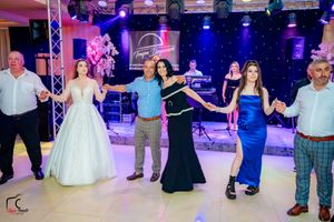 Wedding party dancing in a line on a dance floor with elegant lighting and decor.