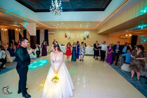 Wedding reception ballroom with elegant lighting and guests gathered around dance floor.