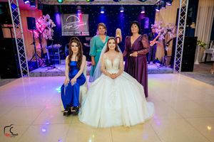 Wedding party members in colorful formal dresses pose together on a decorated dance floor.