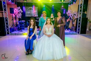 Wedding celebration with colorful lighting and attendees in formal attire posing for photos.