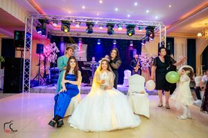 Elegant wedding reception with pink lighting, stage setup, and formal party attire.