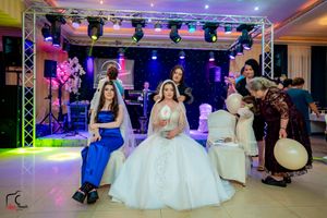 Banquet hall decorated with theatrical lighting and white formal seating arrangements.