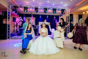 Reception venue with modern lighting system and formal white seating for a celebration.