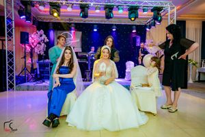 Celebration hall with dramatic purple lighting and formal white party decorations.
