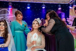 Wedding celebration in a venue with blue and purple lighting and guests dancing on the dance floor.