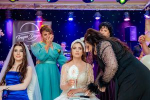 Wedding party dancing and celebrating under vibrant blue and purple stage lighting.